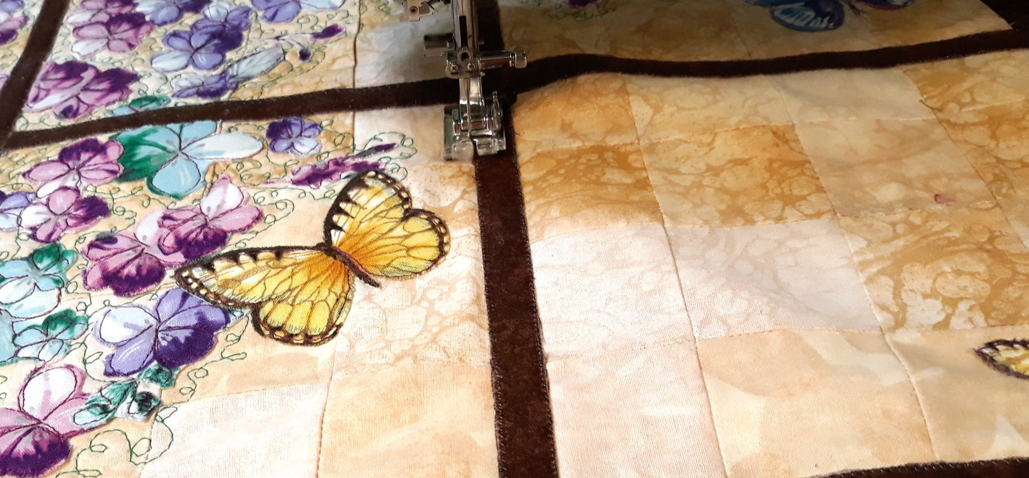 quilt with butterfly and appliqued flowers with the sewing machine in the background